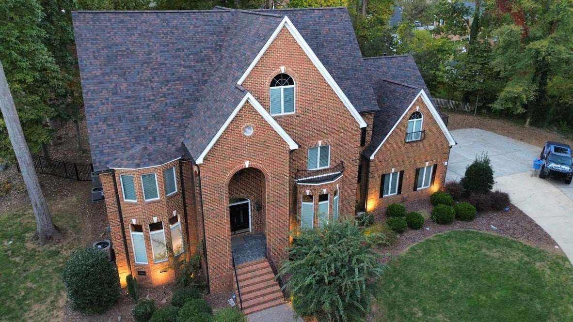 Brick two-story home at dusk with a new Owens Corning designer shingle roof in Bourbon.