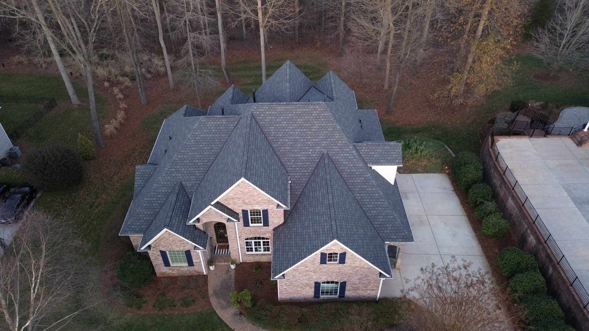 Drone view of a house with many gables and a new gray shingle roof.